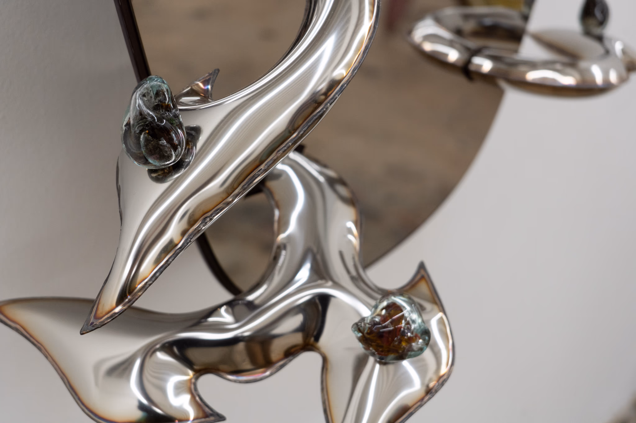 Detail of a polished metallic sculpture at Nina Johnson — curving silver forms with embedded amber stones.