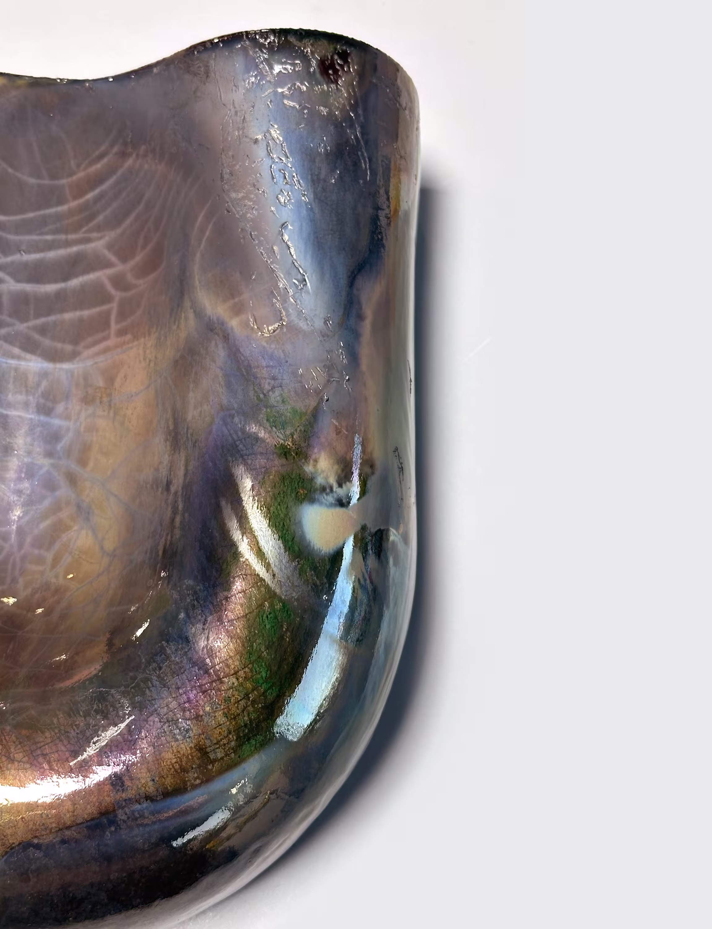 Close-up of a copper Onda sconce with raku finish, showcasing an iridescent texture with intricate crackle patterns and a glossy surface.