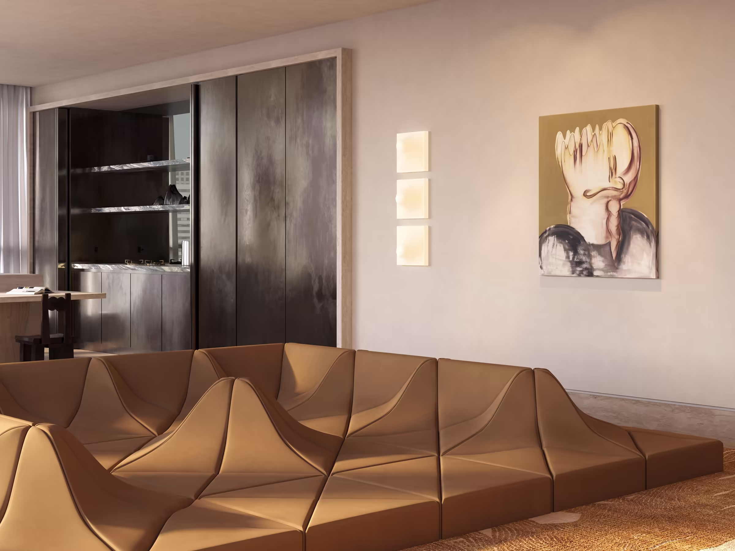 Artful living room featuring a tan Dune sofa by Pierre Paulin with geometric, wave-like forms. Abstract wall art and a trio of vintage space age wall sconces add character. Behind the seating area, dark-toned built-in kitchen and textured walls contrast with soft natural light.