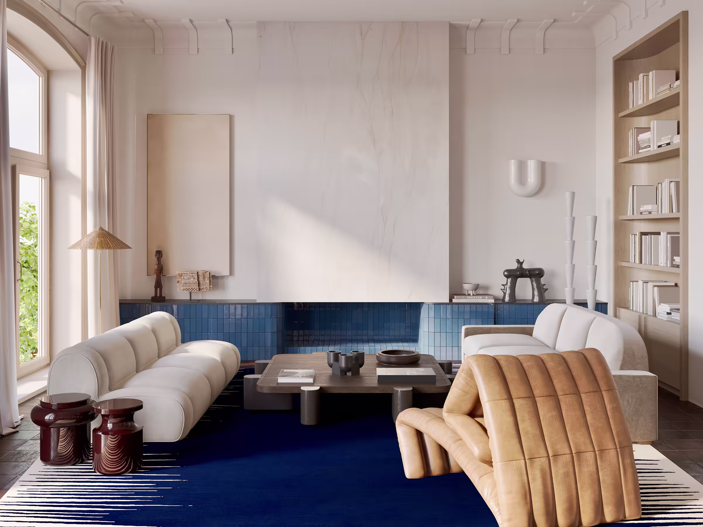 Pale-cream living room with a curved Perriand-style sofa, leather club chair, and a blue tiled console under a fanned paper lamp.